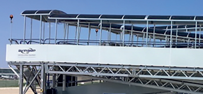 This scene showcases a state-of-the-art airport jet bridge, which is a covered walkway that connects the terminal building directly to an aircraft. Its sleek, modern design features transparent or semi-transparent panels that allow natural light to filter through, creating a bright and welcoming environment for travelers. These jet bridges are equipped with climate control, lighting, and safety features, making the boarding process comfortable regardless of weather conditions. Their design maximizes efficiency—allowing multiple aircraft to be serviced simultaneously—and enhances safety by providing a secure and direct pathway for passengers and crew. The clear blue sky in the background emphasizes the openness and scale of modern airports, highlighting how these structures are integral to global travel. They symbolize seamless connectivity, safety, and the sophisticated infrastructure that keeps air travel smooth and reliable. Truly impressive engineering marvels that facilitate millions of journeys around the world!