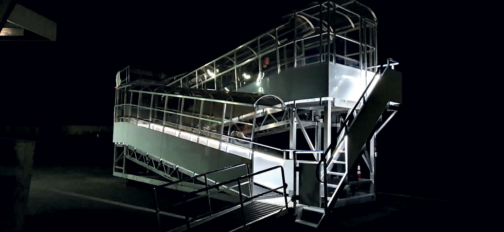 While the scene might seem a bit mysterious or "spooky" at night, it actually captures the quiet, essential side of airport life that often goes unnoticed. The brightly lit boarding staircase or jet bridge stands out sharply against the darkness, creating dramatic shadows and a sense of anticipation. The lighting not only ensures safety and visibility for passengers and crew but also adds a cinematic quality, making the scene feel almost like a moment from a suspenseful movie. In reality, airports operate 24/7, and nighttime scenes like this are bustling with activity behind the scenes—security checks, aircraft servicing, and crew preparations—though they often go unseen by travelers. The quiet, illuminated walkway hints at stories of travelers heading to exciting destinations or returning home after adventures. So, while it might look a little spooky or mysterious, it's really a vital part of the global travel network, symbolizing movement, transition, and the endless journeys that connect the world.