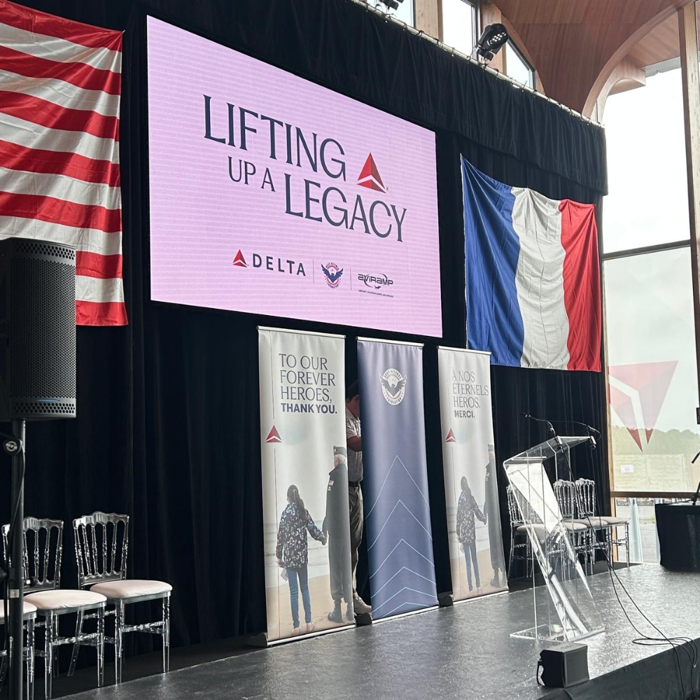 The stage is set for the “Lifting Up a Legacy” ceremony, where Delta and its partners pay tribute to World War II veterans—surrounded by symbols of gratitude and unity, and a powerful message: “To our forever heroes. Thank you.”