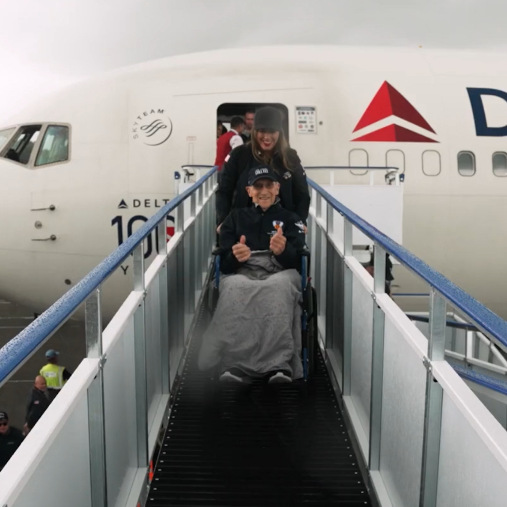 A war veteran gives a big thumbs-up whilst being wheeled from a Delta Airlines flight.