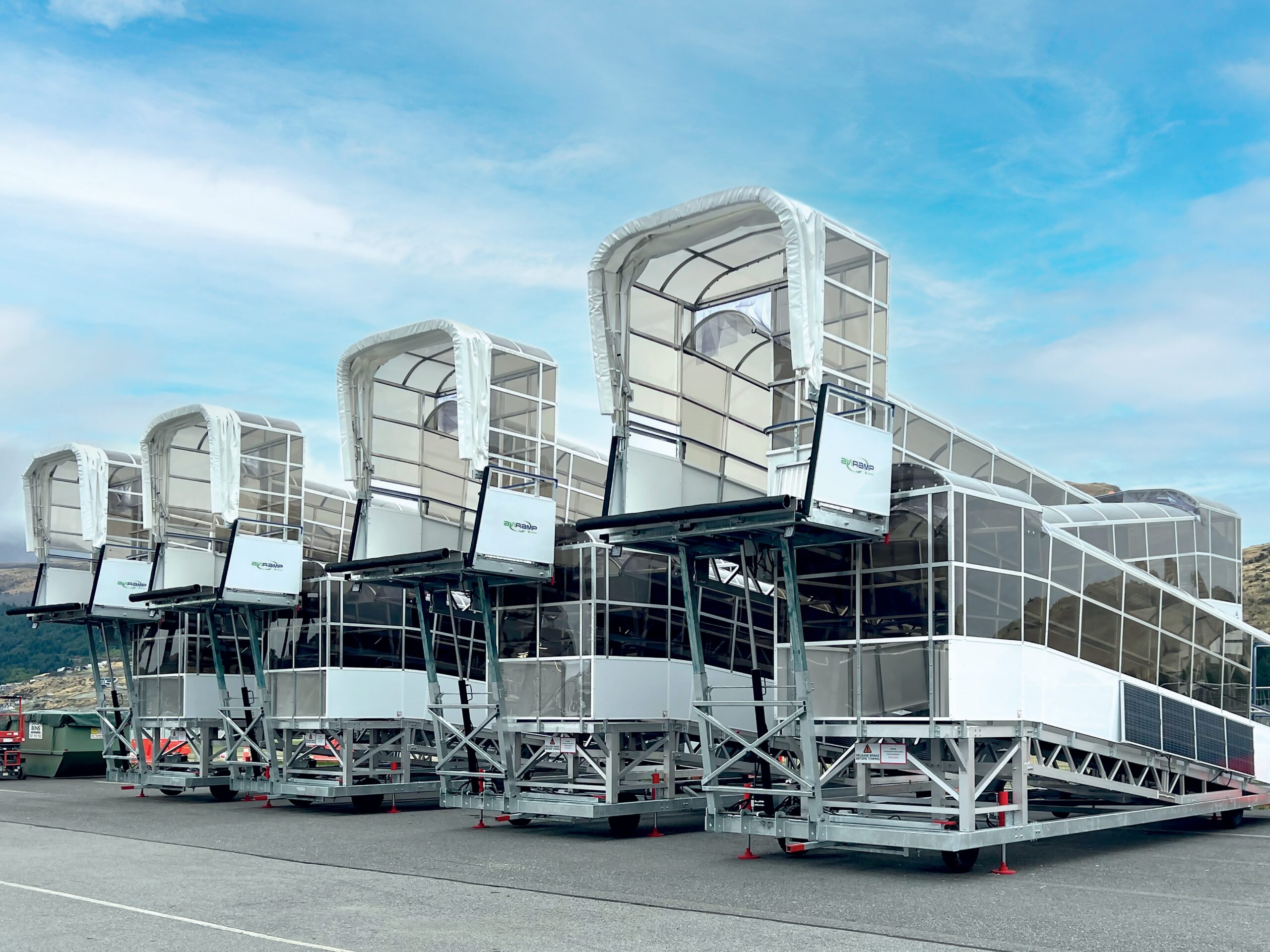 several airport jet bridges are stacked and not currently in use. They are positioned on the tarmac, prepared to be deployed to connect with aircraft for passenger boarding and disembarking. This setup indicates readiness for airport operations, possibly during a period of low activity or before scheduled flights.