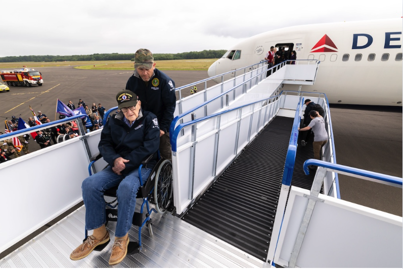 US WWII veteran in a wheelchair disembarking a Delta Air Lines plane using an Aviramp