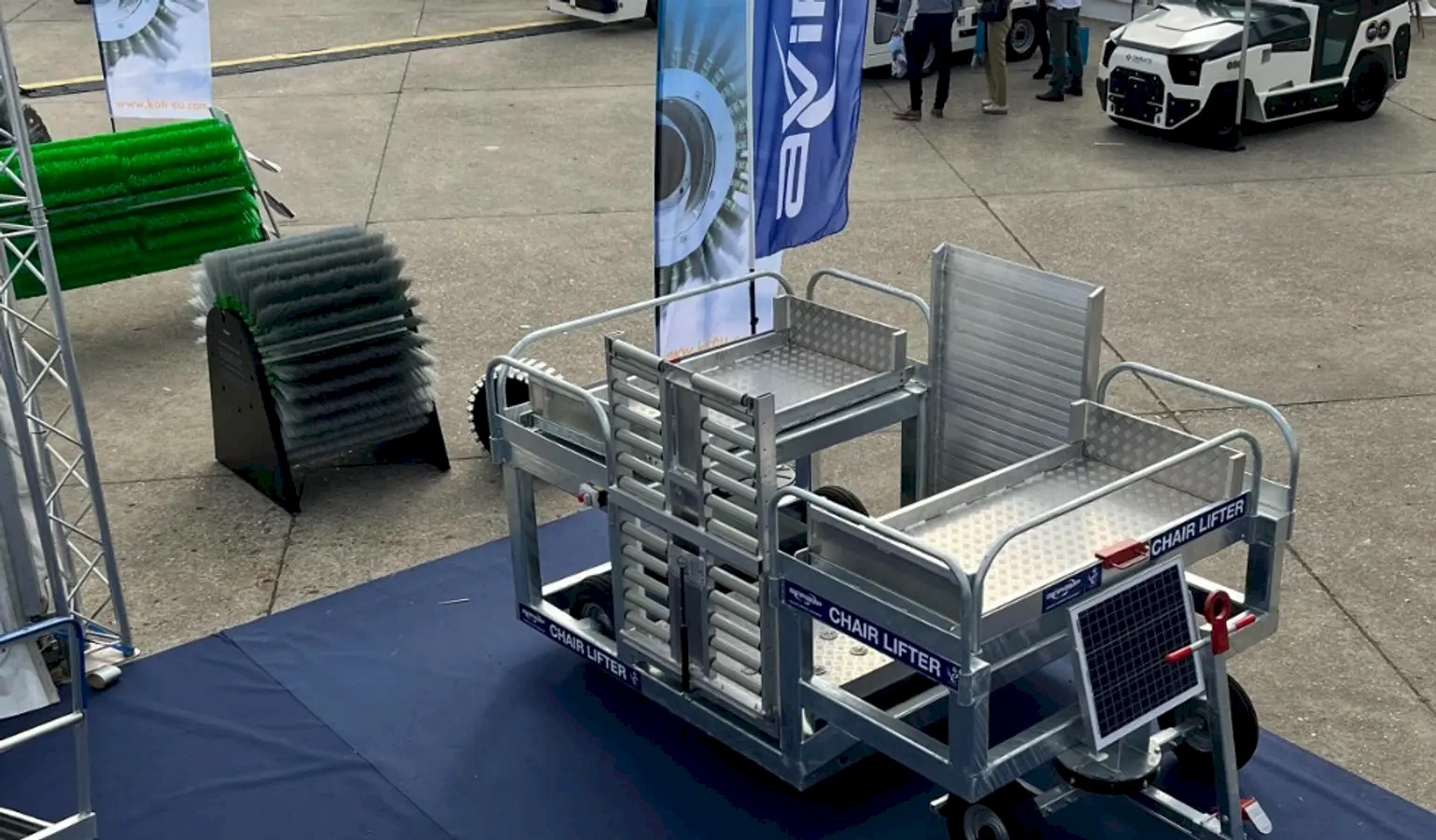 Airline ground support equipment, such as a chair lift cart and cleaning brushes, showcased at an aviation event.