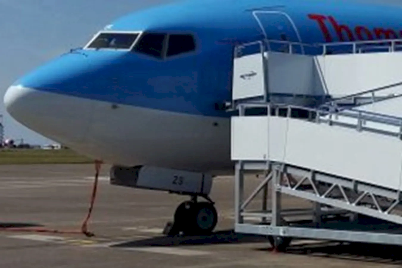An airplane moving along the runway, likely during taxiing, with a mobile stairway attached to facilitate passenger boarding or disembarking. The scene suggests active airport operations, with the aircraft on the ground ready for or just after a flight. The background may include airport infrastructure or other aircraft, emphasizing the busy environment of air travel.