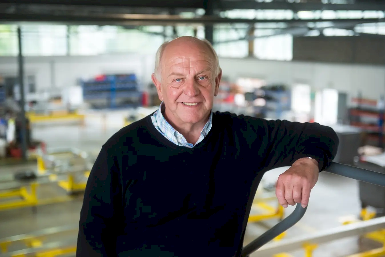 His confidence, experience, and approachability, embodying the spirit of a seasoned professional who’s comfortable in his environment. His relaxed smile and casual stance suggest he's at ease, perhaps enjoying the moment amidst a busy industrial setting.